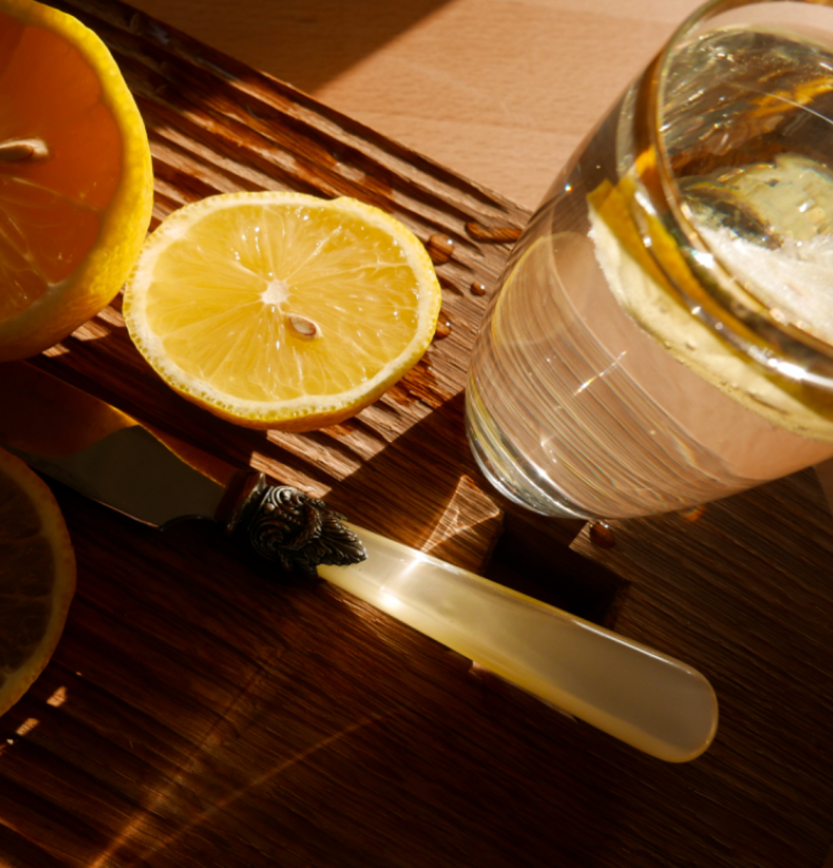Lemon and a glass of water on a wooden table for The Beauty Sleeper’s Hydration & Sleep